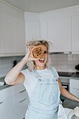 Lächelnde Frau in der Küche mit Keks in der Hand