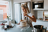 Woman in kitchen decorating cake