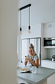 Woman using cell phone in kitchen