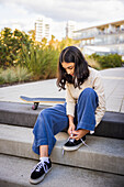 Girl skateboarder tying shoes