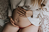 Schwangere Frau hält Hände auf Bauch
