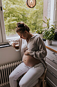 Schwangere Frau trinkt Kaffee in der Küche