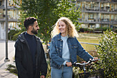 Young couple walking with bike in residential area