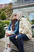 Älteres Paar sitzt auf einer Bank und küsst sich
