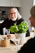 Porträt eines lächelnden älteren Mannes, der am Tisch sitzt