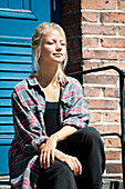 Young woman sitting in stairs in front of house