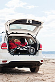 Kinderwagen im Kofferraum eines Autos am Strand am Meer