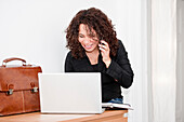 Woman using laptop and talking on phone