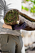 Man holding rolled up sod