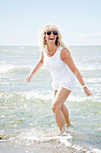 Blonde Frau spielt am Strand