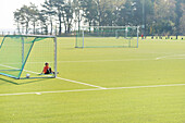 Boy sitting on football pitch
