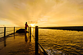 Person on jetty at sunset