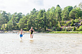 Mutter und Sohn laufen durchs Wasser