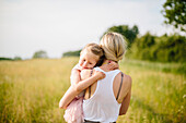 Mother carrying daughter in meadow