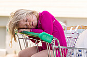 Girl sitting in shopping trolley and sleeping