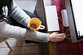 Woman holding mug, using computer