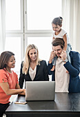 People using laptop, father giving daughter piggyback