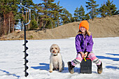 Mädchen sitzend auf Eis mit Hund