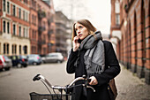 Young woman with bicycle on the phone
