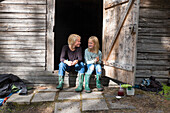 Girl and teenage boy sitting in front of barn