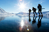 Three people skiing on frozen lake