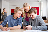 Teenager schauen auf ein Handy im Klassenzimmer
