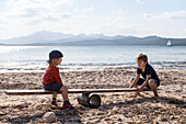 Boys playing seesaw on beach