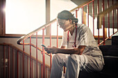 Ärztin auf der Treppe sitzend mit Smartphone