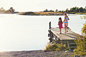 Mädchen gehen auf dem Pier am See spazieren