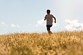 Boy running through meadow