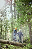 Boys in forest walking on tree trunk