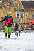 Junge läuft mit Hund im Winter