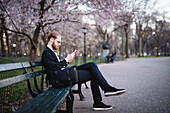 Mann liest auf einer Bank im Park