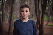 Porträt eines ernsten Jungen im Wald