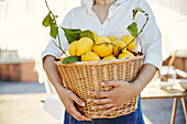 Frau hält Korb voller Zitronen