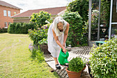 Senior woman watering flowers in garden