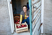 Smiling woman with crate full of apples