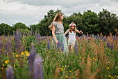 Mother and daughter walking through meadow