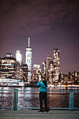 Woman taking picture of illuminated skyscrapers