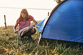Young woman putting tent up