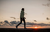 Junger Mann joggt am Strand bei Sonnenuntergang
