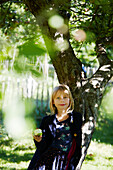 Blondes Mädchen isst Apfel im Obstgarten