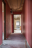 Verlassener roter Korridor in Wohnung während Renovierung