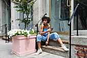 Young woman sitting on steps with mobile phone