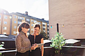 Lächelnde Kollegen auf der Terrasse mit digitalem Tablet