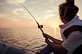 Frau fischt bei Sonnenuntergang