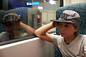 Junge sitzt im Zug und schaut durch das Fenster