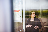 Pregnant woman sitting at bus station