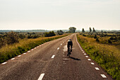 Person cycling on country road