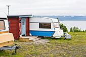Travel trailer and wooden cottage by lake
